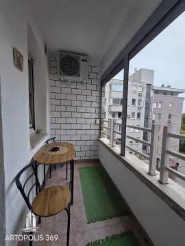 Natkriveni balkon sa garniturom za sedenje i pogledom na okolne zgrade. - image 17