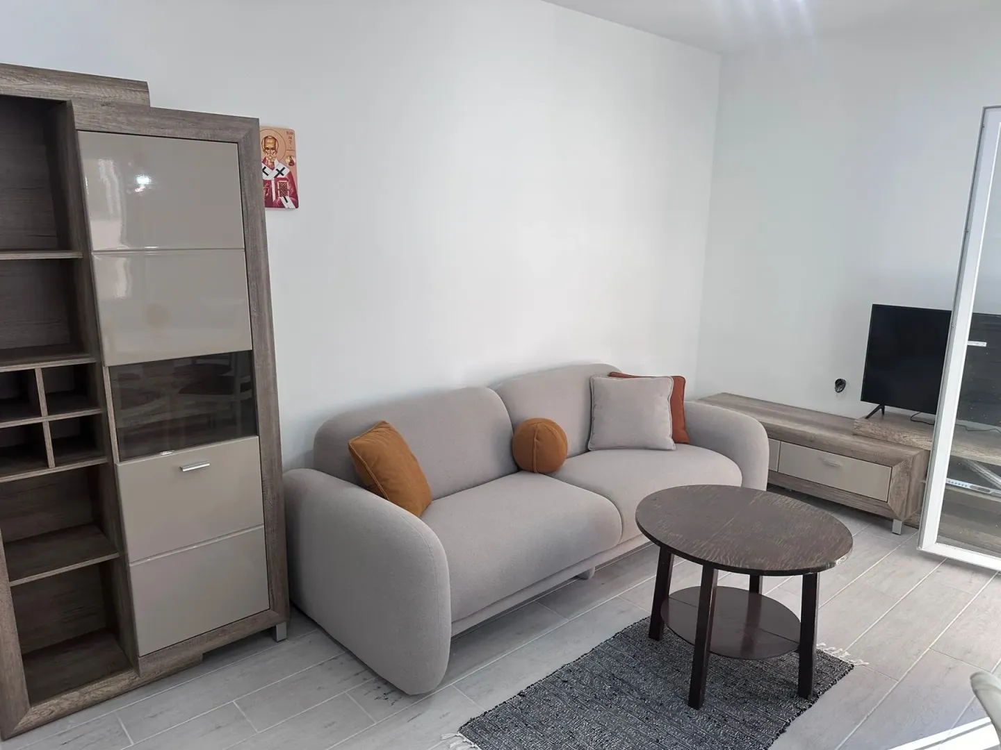 Living room furnished with a sofa, shelving unit, coffee table, and television.