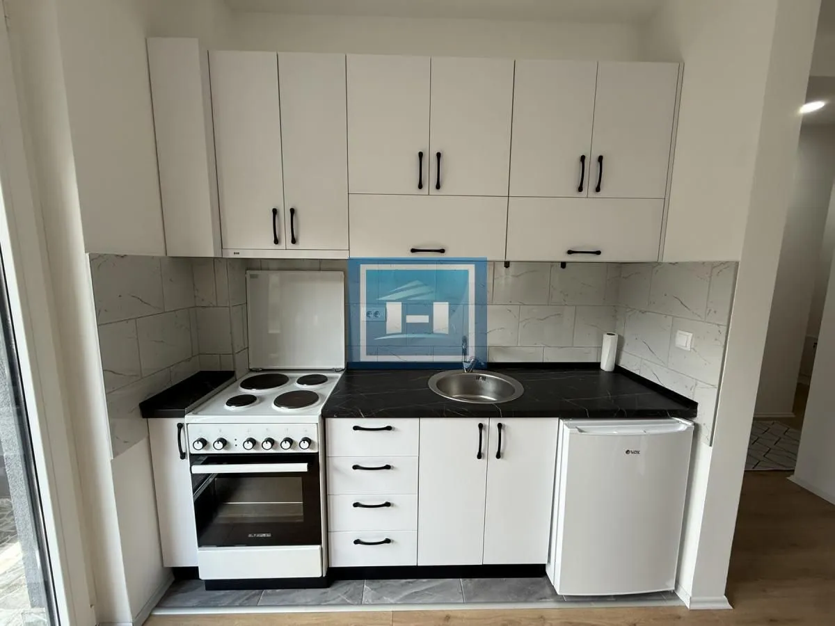 Small white kitchen with a stove, sink, and refrigerator.