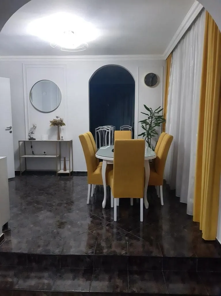 Dining area with a table and yellow chairs within the living room.