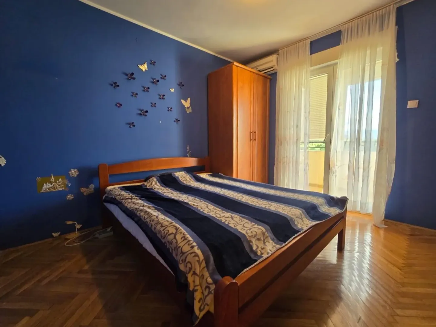 Bedroom with a double bed, wooden wardrobe, and a blue accent wall.