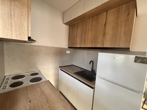 Small kitchen with wooden cabinets, sink, and electric stove. - image 4