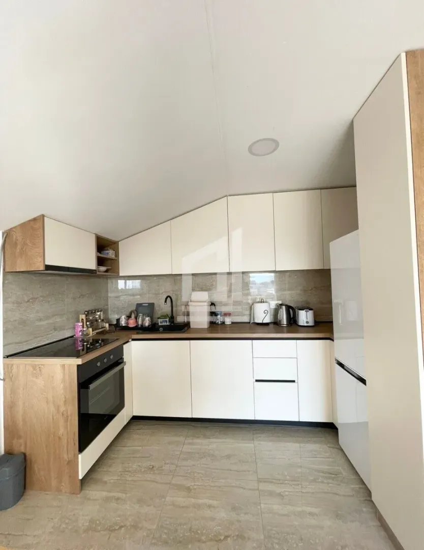 Small kitchen in bright tones with built-in appliances and wooden countertops.