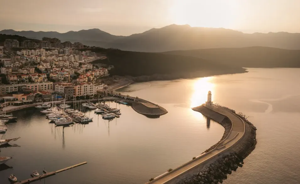Pogled iz vazduha na obalu sa marinom i svjetionikom u zalasku sunca.