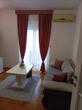 Svijetla dnevna soba sa sivom garniturom, bijelim klupskim stolom i ružičastim zavjesama. - image 2