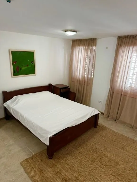 Bedroom with a double bed, bedside table, and windows with curtains.