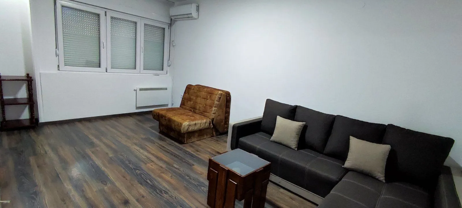 Living room with a sectional sofa, an armchair, and laminate flooring.