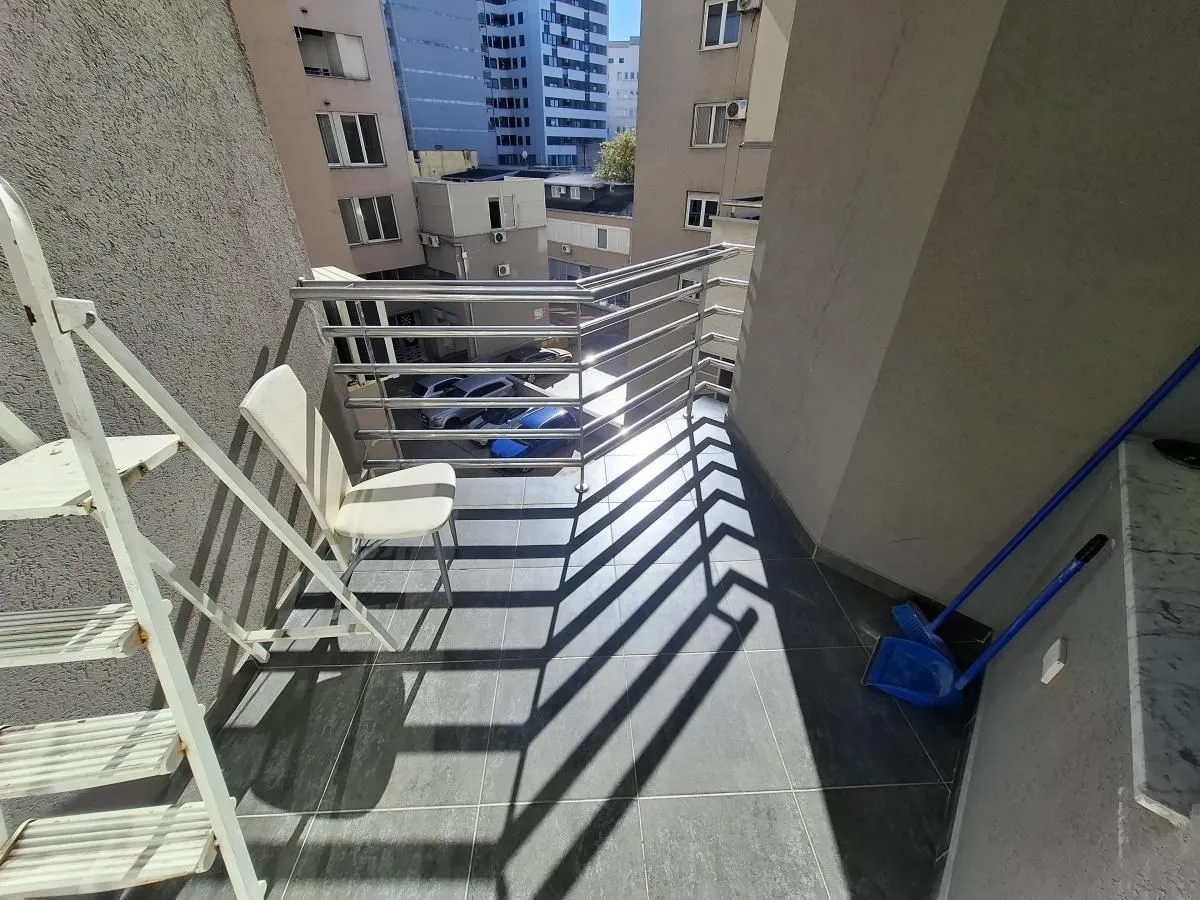 Manji popločani balkon sa metalnom ogradom i pogledom na okolne zgrade.