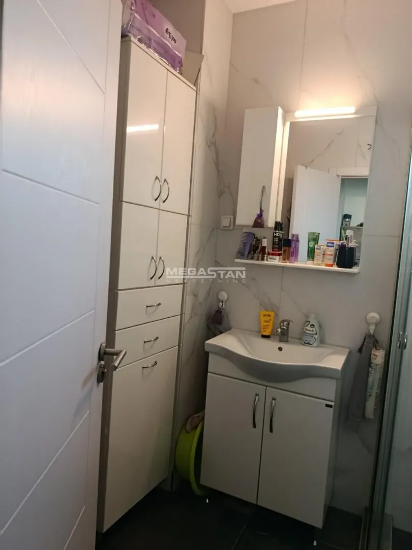 Smaller bathroom with a washbasin, mirror and white storage cabinet.