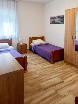 Bedroom with two single beds and a wooden wardrobe. - image 4