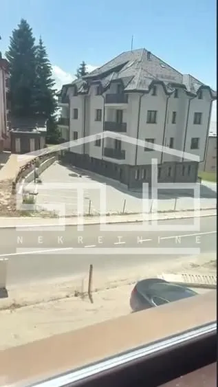 Pogled sa prozora na zgradu i parking ispred objekta.
