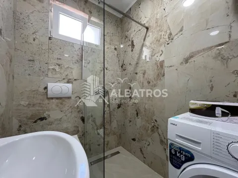 Modernly equipped bathroom with a walk-in shower and washing machine. - image 9