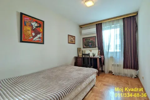 Nameštena spavaća soba sa krevetom, radnim stolom i umetničkim slikama na zidu. - image 6