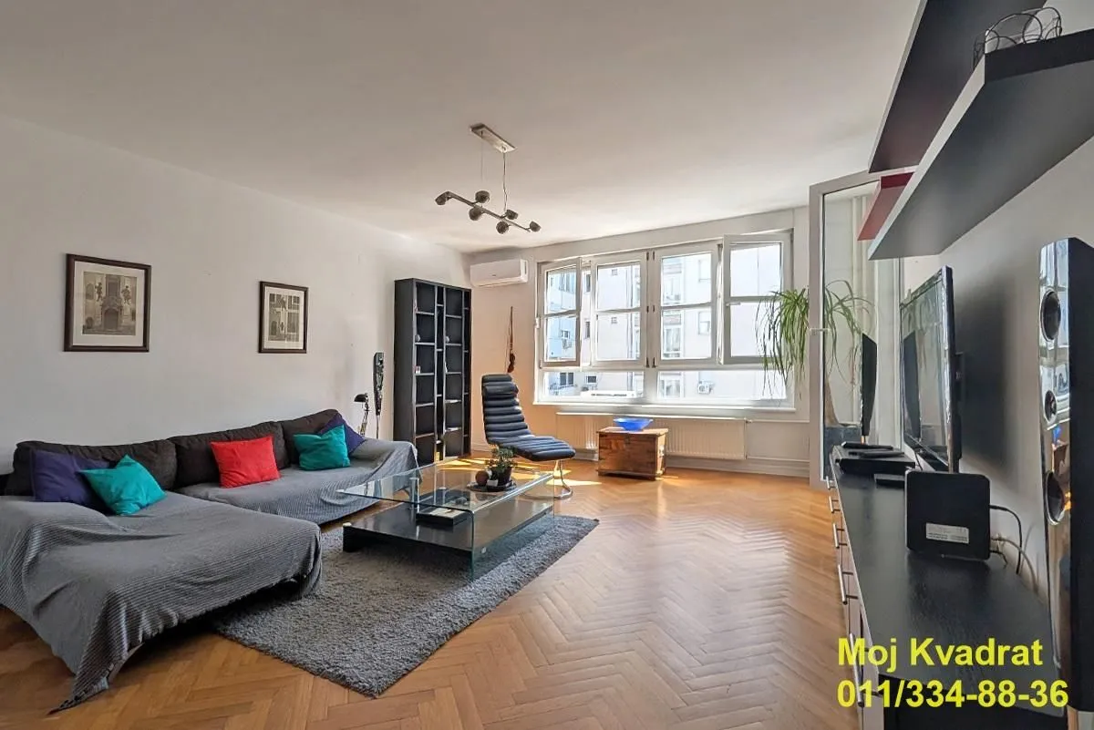 Spacious living room with sofa, parquet flooring and large windows.