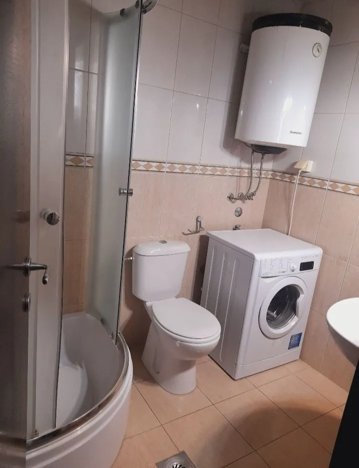 Kupatilo opremljeno tuš kabinom, toaletom i veš mašinom.