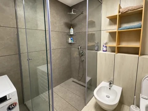 Modern bathroom with a walk-in shower, bidet, and storage shelves. - image 8