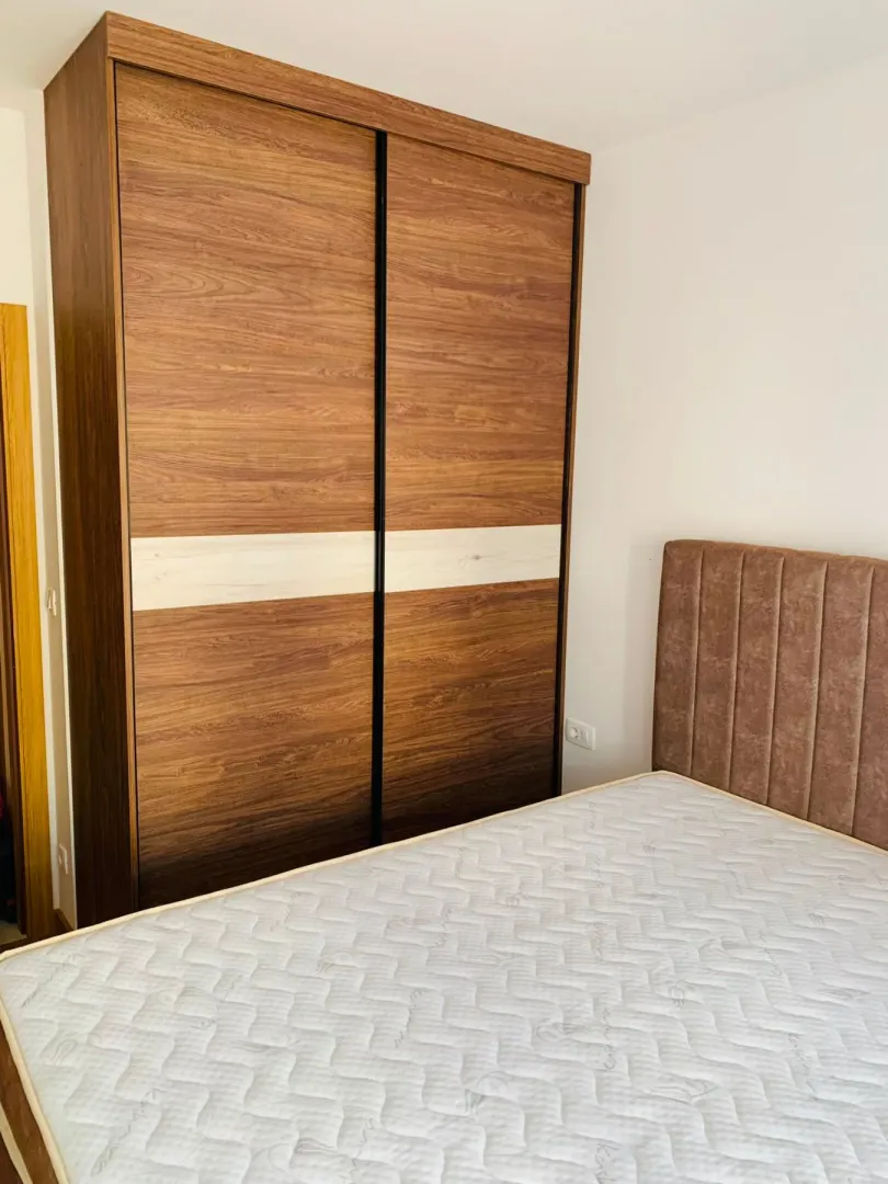 Bedroom with a large double bed and a wooden wardrobe.