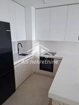 Modern white kitchen with built-in appliances and a black refrigerator. - image 8