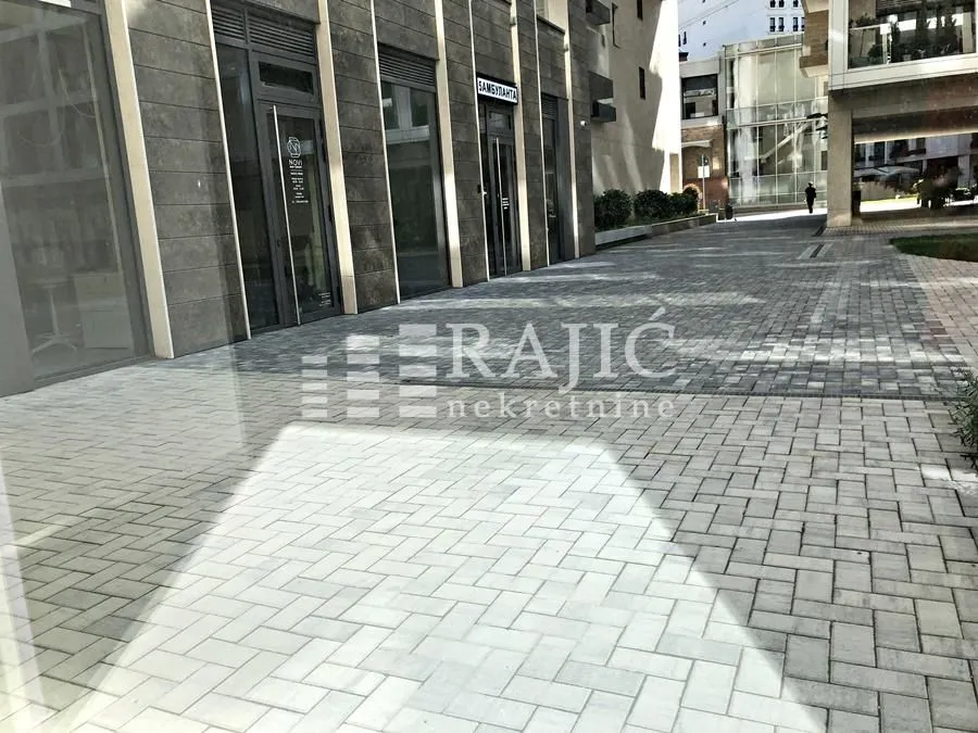 Exterior of a commercial space with a paved courtyard and glass storefront.