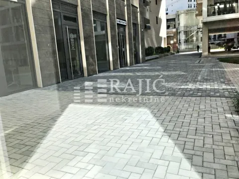 Exterior of a commercial space with a paved courtyard and glass storefront. - image 5