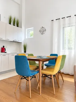 Dining area with a wooden table and colorful chairs next to the kitchen. - image 16