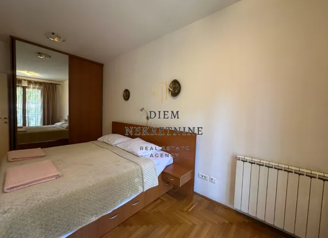 Furnished bedroom with a double bed, wardrobe, and parquet flooring.