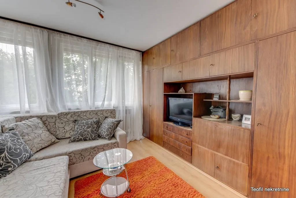 Living room with a sofa set, large wooden wardrobe, and television.