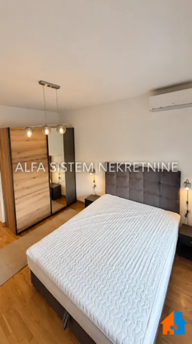 Nameštena spavaća soba sa bračnim krevetom, garderoberom i klima uređajem.