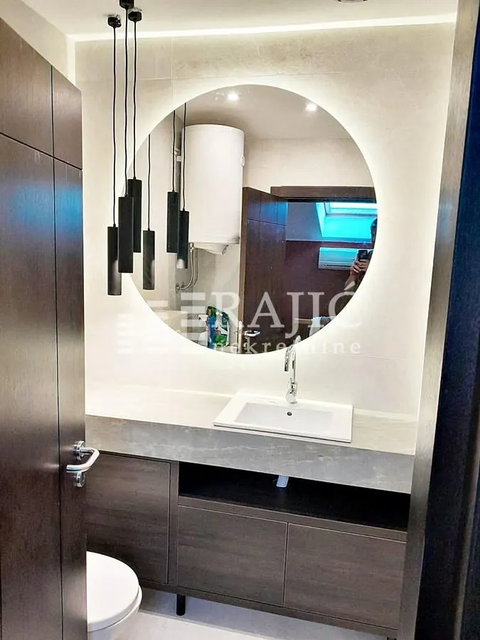 Modern bathroom with a sink, mirror, and pendant lights.
