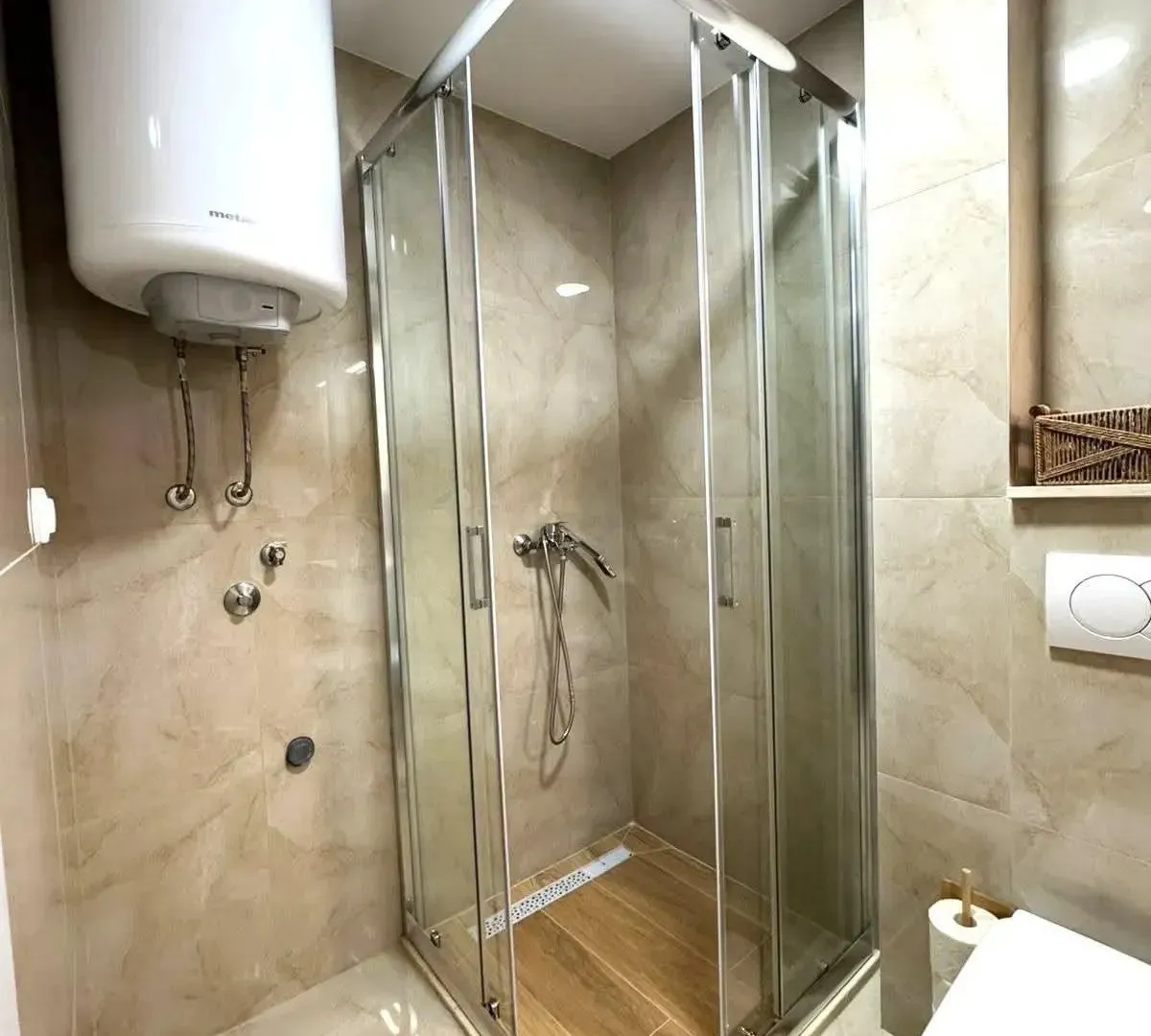 Bathroom with a shower cabin, water heater, and sanitary ware.