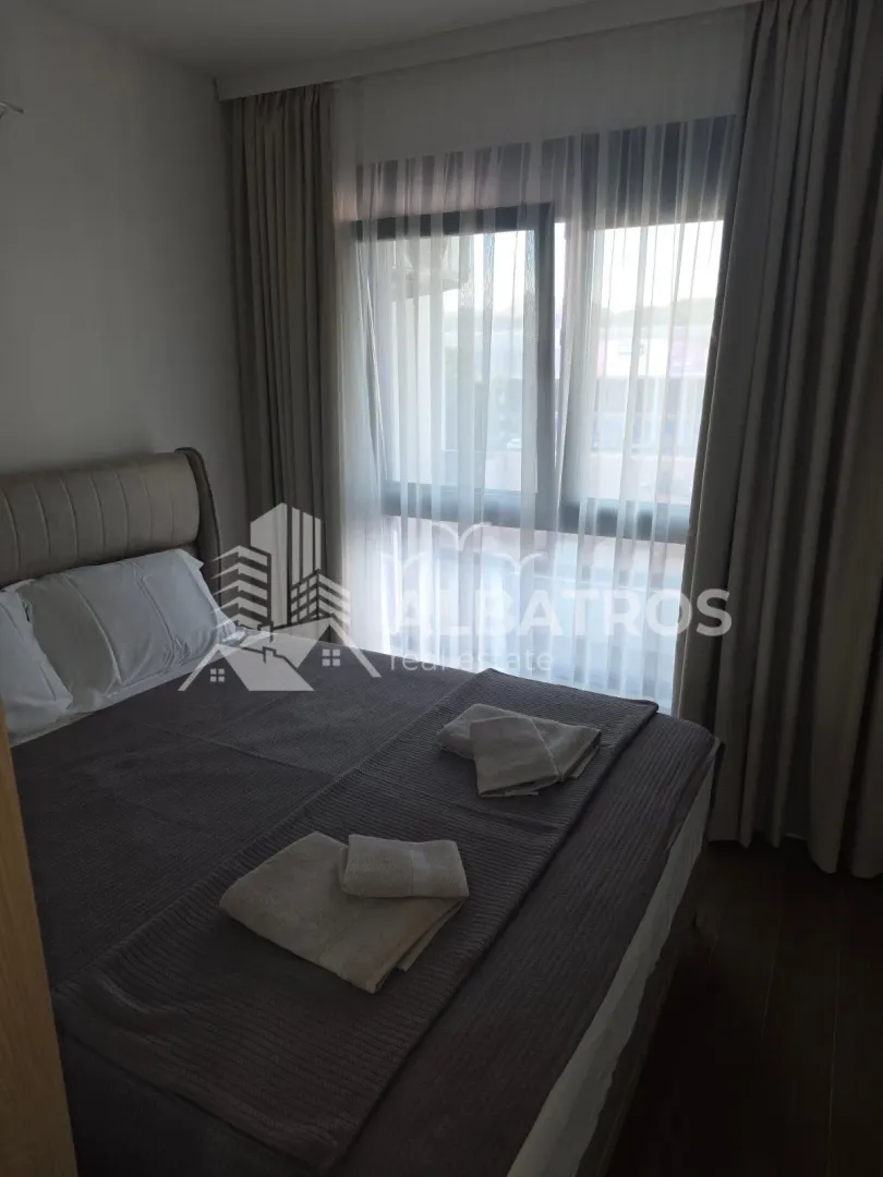 Furnished bedroom with a double bed and a window covered with curtains.