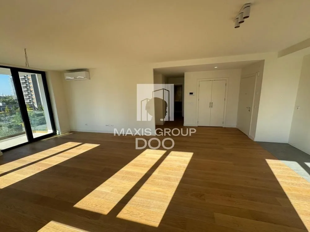 Spacious empty living room with wooden flooring and a large window.