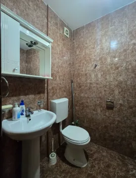 Manje kupatilo obloženo smeđim keramičkim pločicama sa umivaonikom i wc šoljom. - image 9