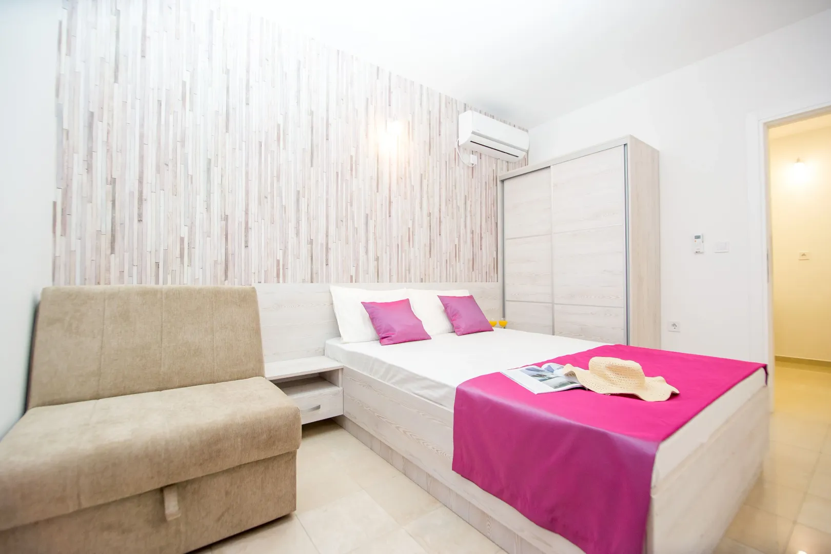 Bright bedroom with a double bed, wardrobe, and couch.
