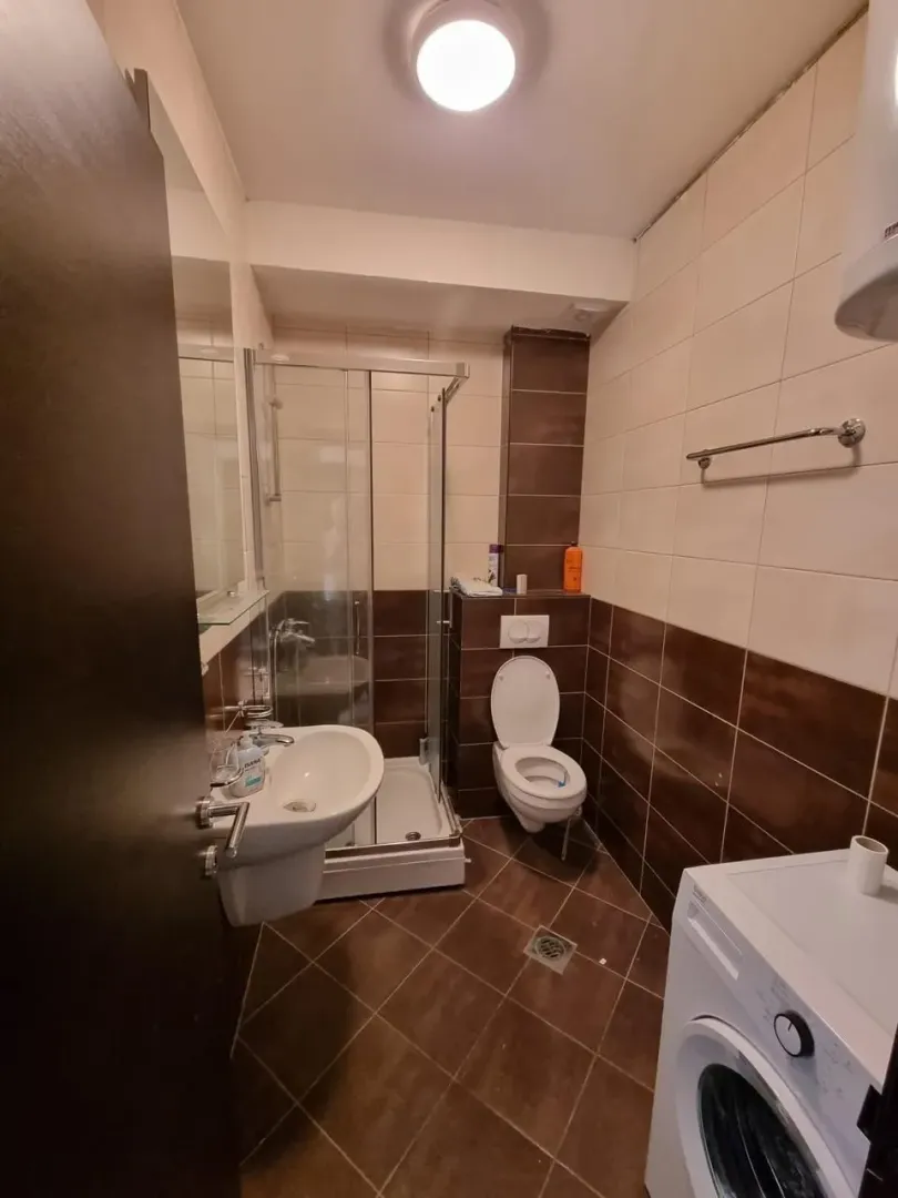 Kompaktno kupatilo sa tuš kabinom, umivaonikom, WC šoljom i veš mašinom.
