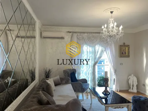 Living room with a sofa set, large mirror, and chandelier. - image 7
