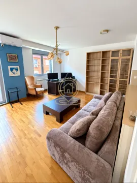 Living room with a sofa, a desk, and a large wooden bookcase. - image 10