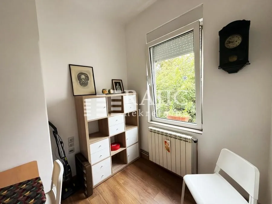 Small room with a desk, shelving unit, and a window.