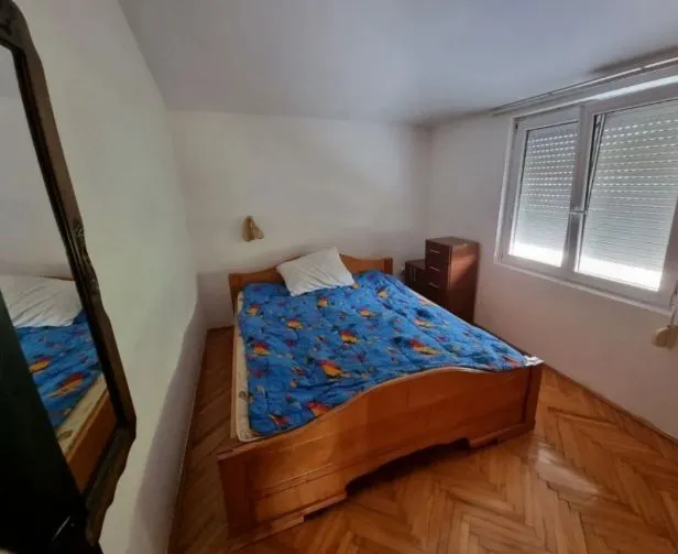 Svijetla spavaća soba sa drvenim krevetom i prozorom.