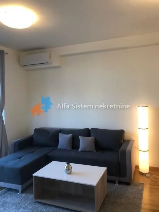 Living room with a sectional sofa, coffee table, and air conditioning unit.
