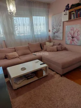 Living room with a sectional sofa, coffee table, and decorative paintings on the wall. - image 2