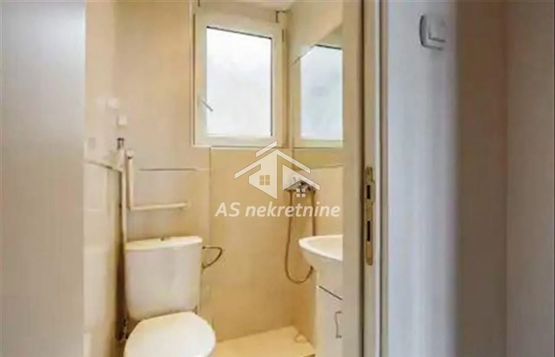 Smaller bathroom with a toilet, sink, and window.