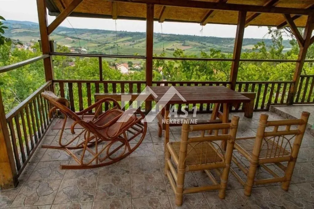 Natkrivena terasa sa drvenim nameštajem i pogledom na prirodu.