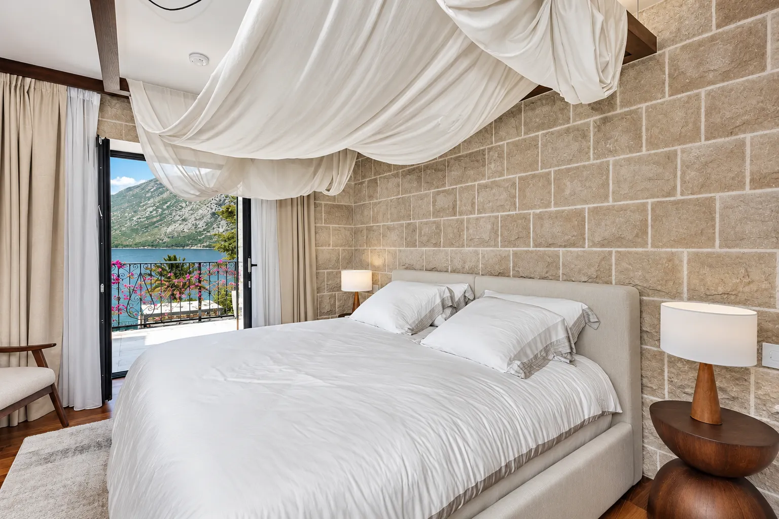 Bedroom with a double bed, stone wall, and a sea view.