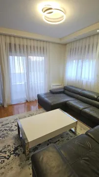 Dnevna soba sa garniturom, stočićem i prozorima sa zavjesama. - image 2