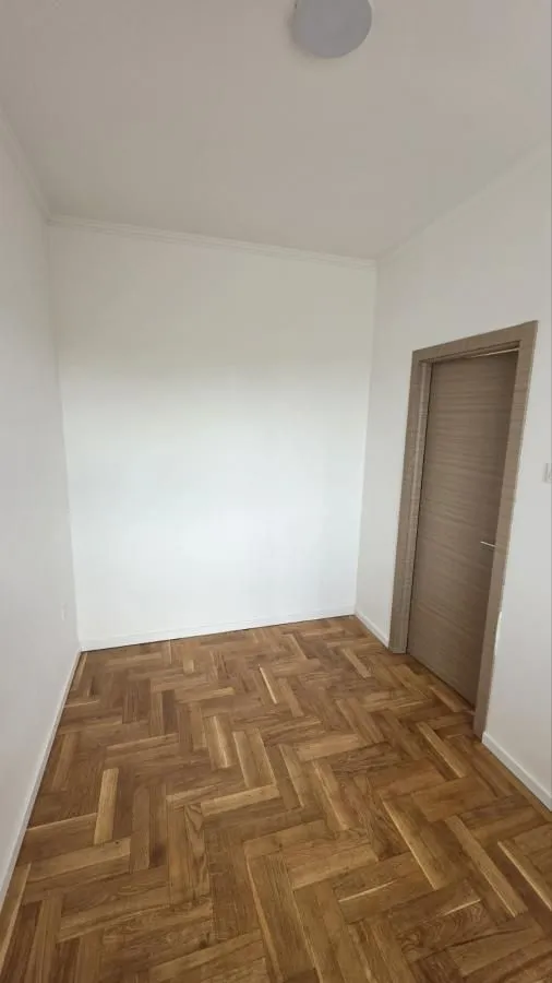Prazna prostorija sa parketom i unutrašnjim vratima.
