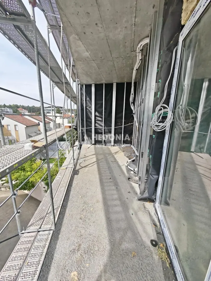 Nezavršeni balkon u izgradnji sa skelama i pogledom na okolinu.