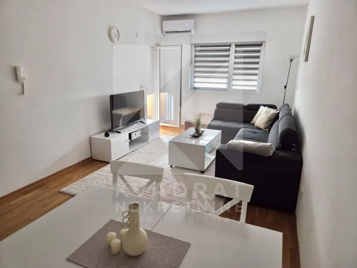 Living room with a sofa, TV, and dining table.