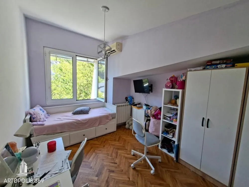 Dečja soba sa krevetom, radnim stolom i ormanom.