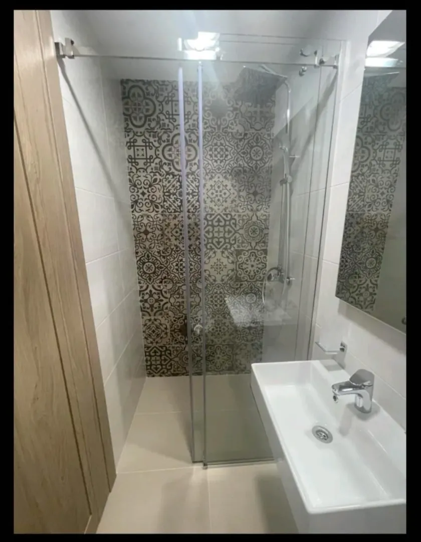 Moderne kupatilo sa tuš kabinom i umivaonikom.